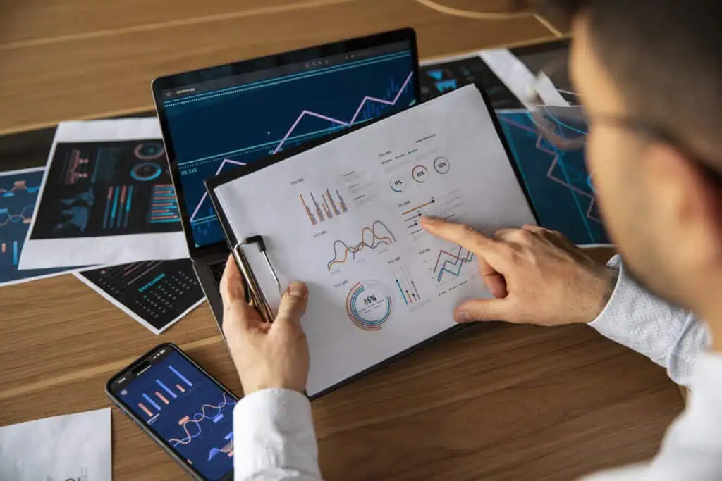 Office worker using graphs on paper, tablet and phone