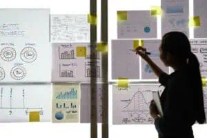 Business woman analyzing charts and graphs hanging on a glass wall