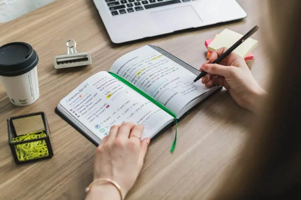 Woman writting daily business goals in notebook