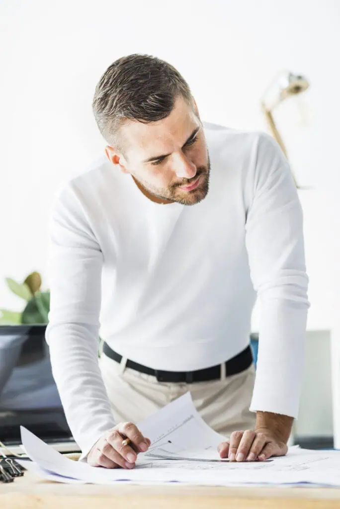 Project manager standing above papers scatered on a desk