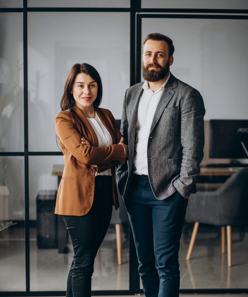 Two COOs, woman and man, stand next to each other in an office
