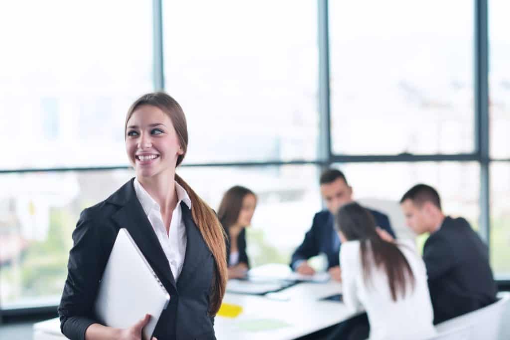 Group of interim managers in a meeting room, with smiling woman holding files in the forefront